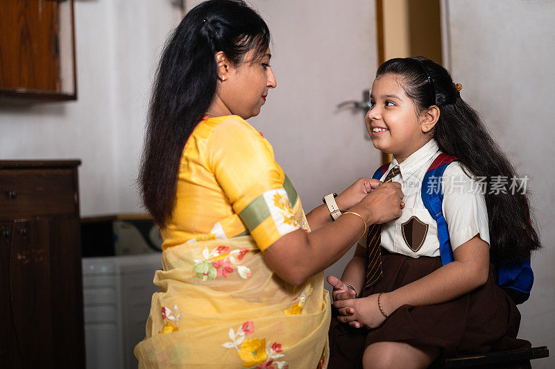 亚洲/印度母亲帮女儿打扮去上学。